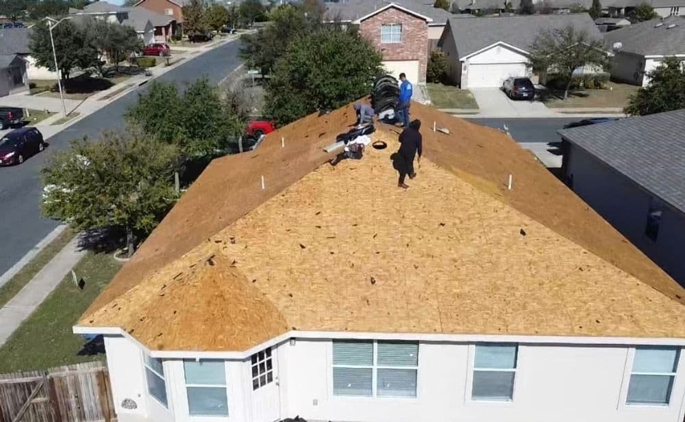 Roof replacement in progress with workers on a residential home in a suburban neighborhood.