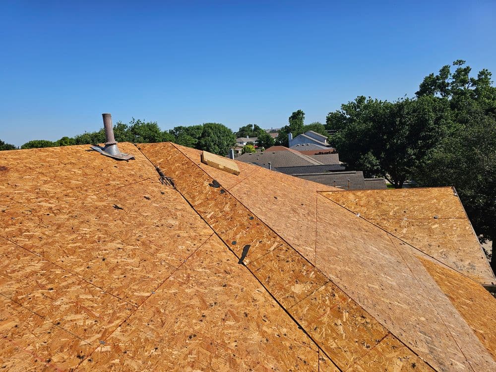 Newly installed OSB roof sheathing on a residential home with clear blue sky above.