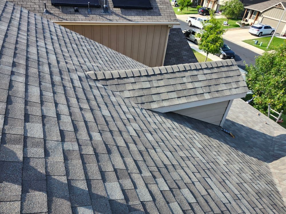 Aerial view of a residential roof featuring gray shingles and a sloped design.